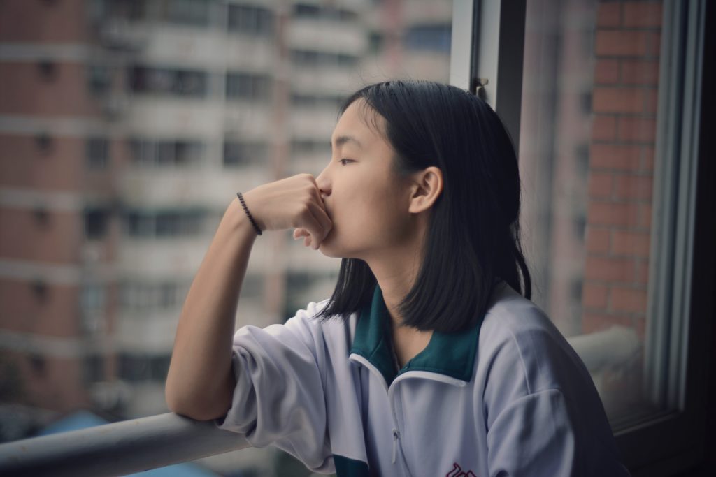 woman looks longingly out a window